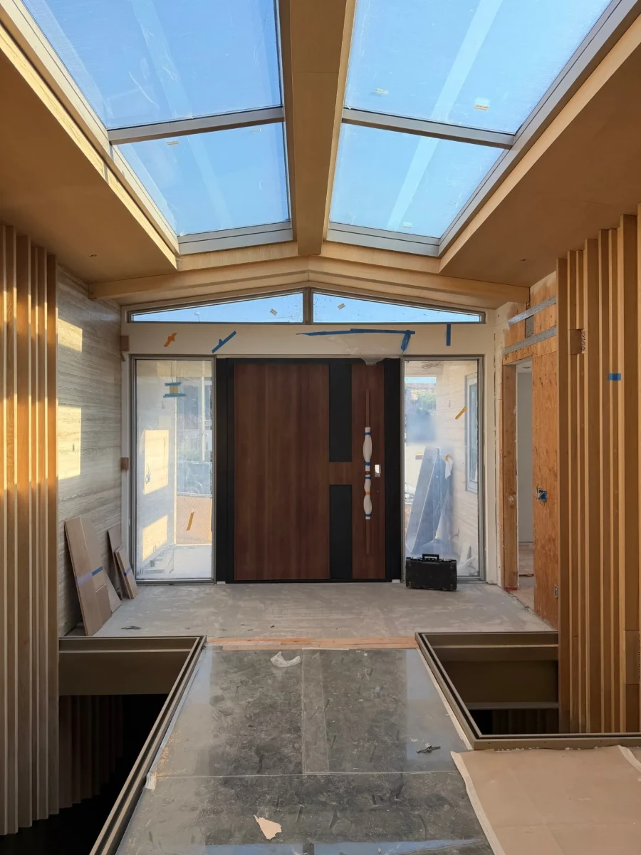 Custom pivot entry door from our 2026 Corona del Mar project, installed between glass sidelites
