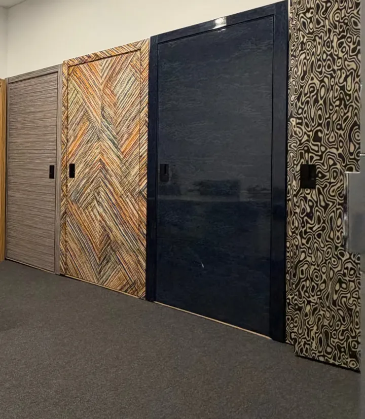 Four display doors at our La Mirada warehouse: gray veneer, multicolor chevron, navy gloss and a patterned burl-look face, each in its frame
