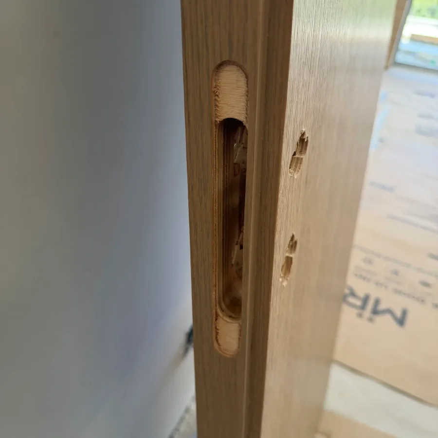Wood veneer door edge with a mortise lock pocket and pre-bored hardware holes